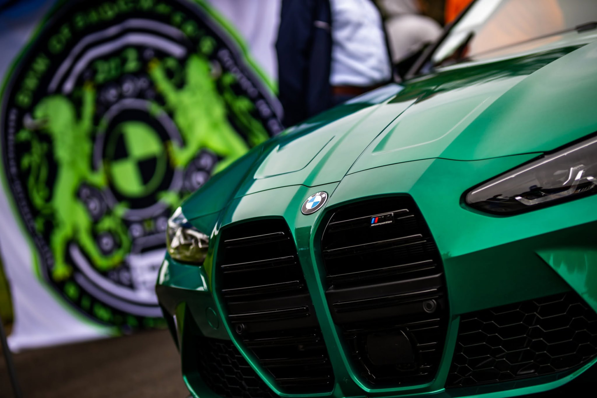 Green BMW M3 Competition front end beside the BimToberFest crest banner