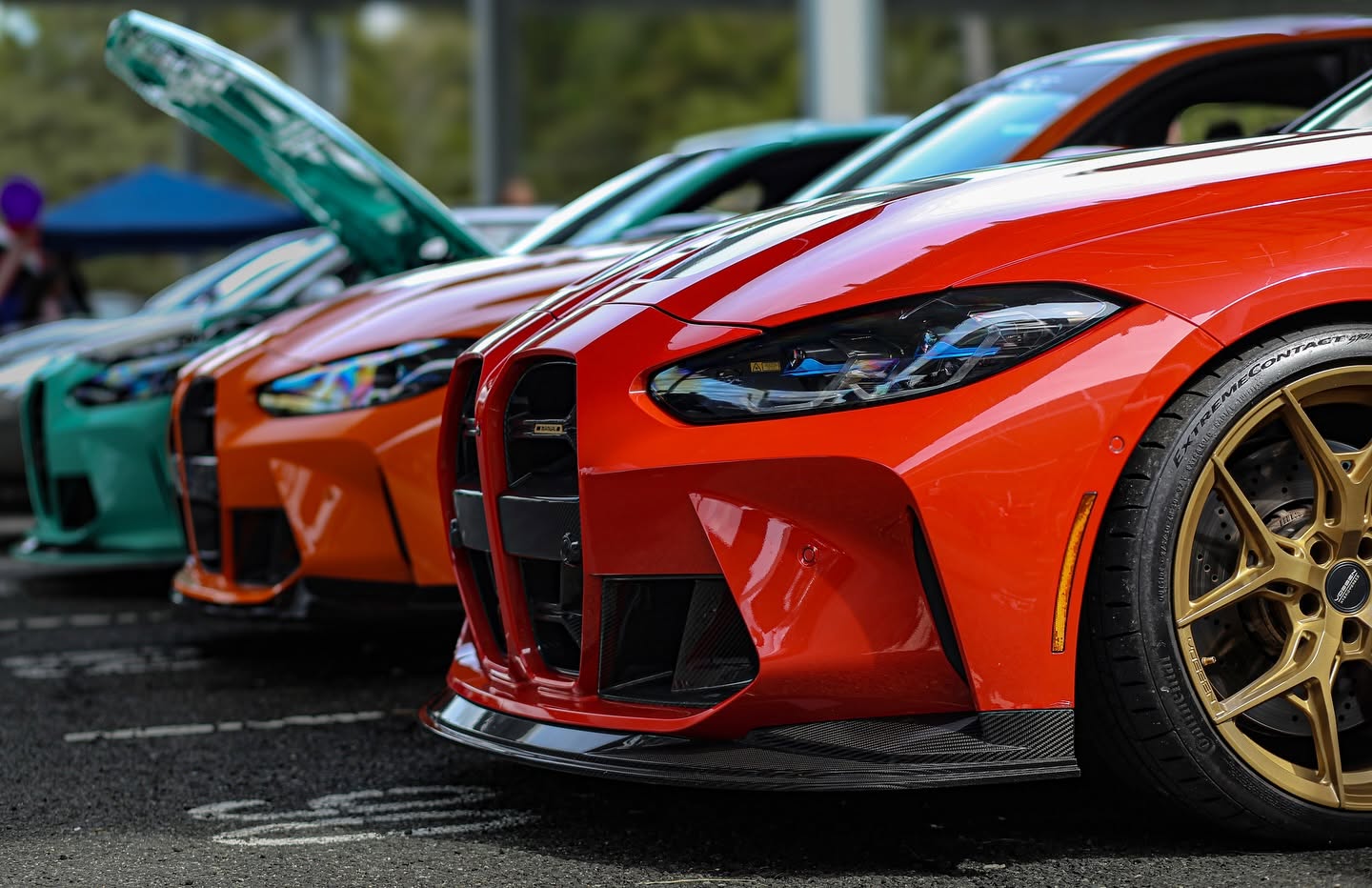 Red, orange and mint BMW M4s lined up nose to nose